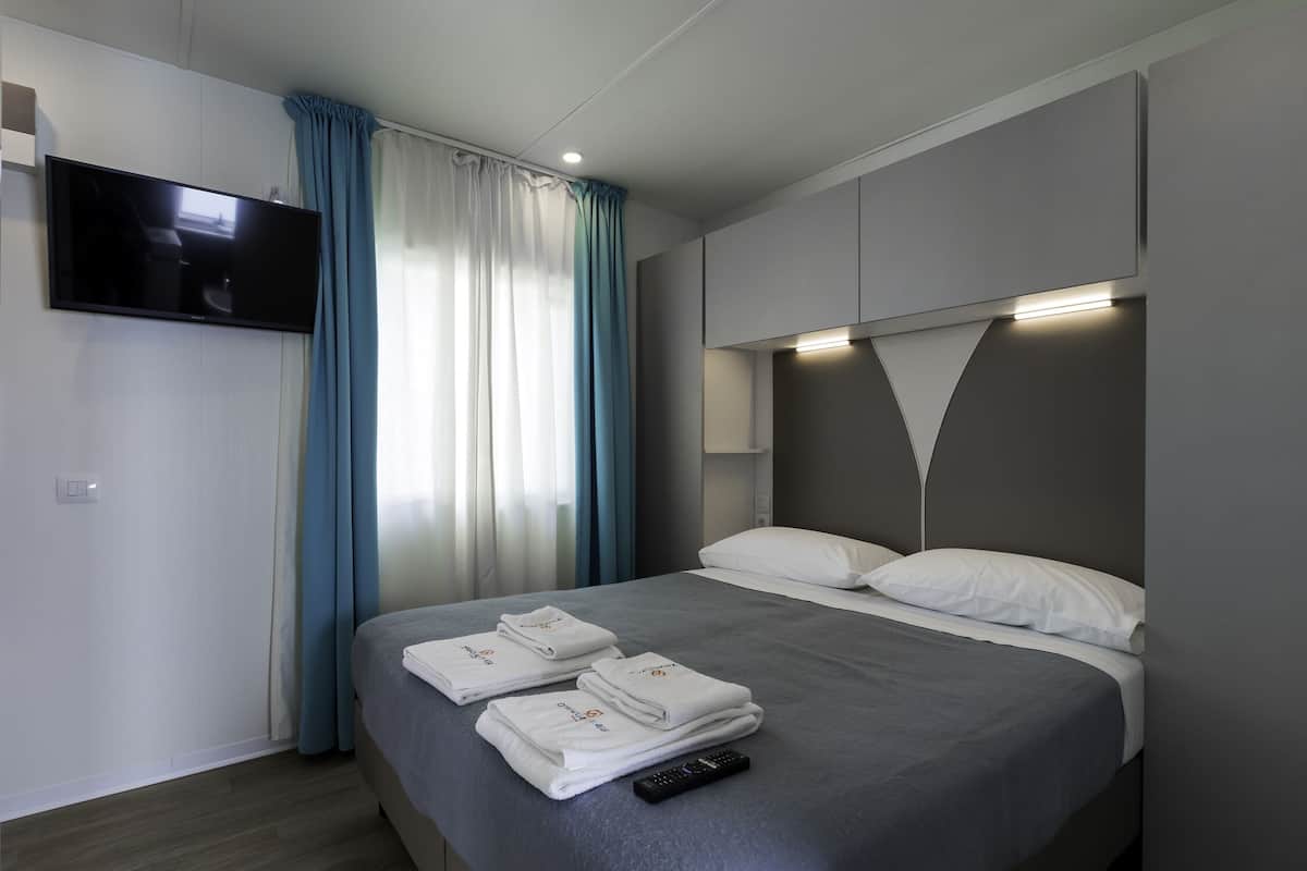 Een moderne hotelkamer met een bed, een flatscreen televisie aan de muur en een afstandsbediening op het bed.