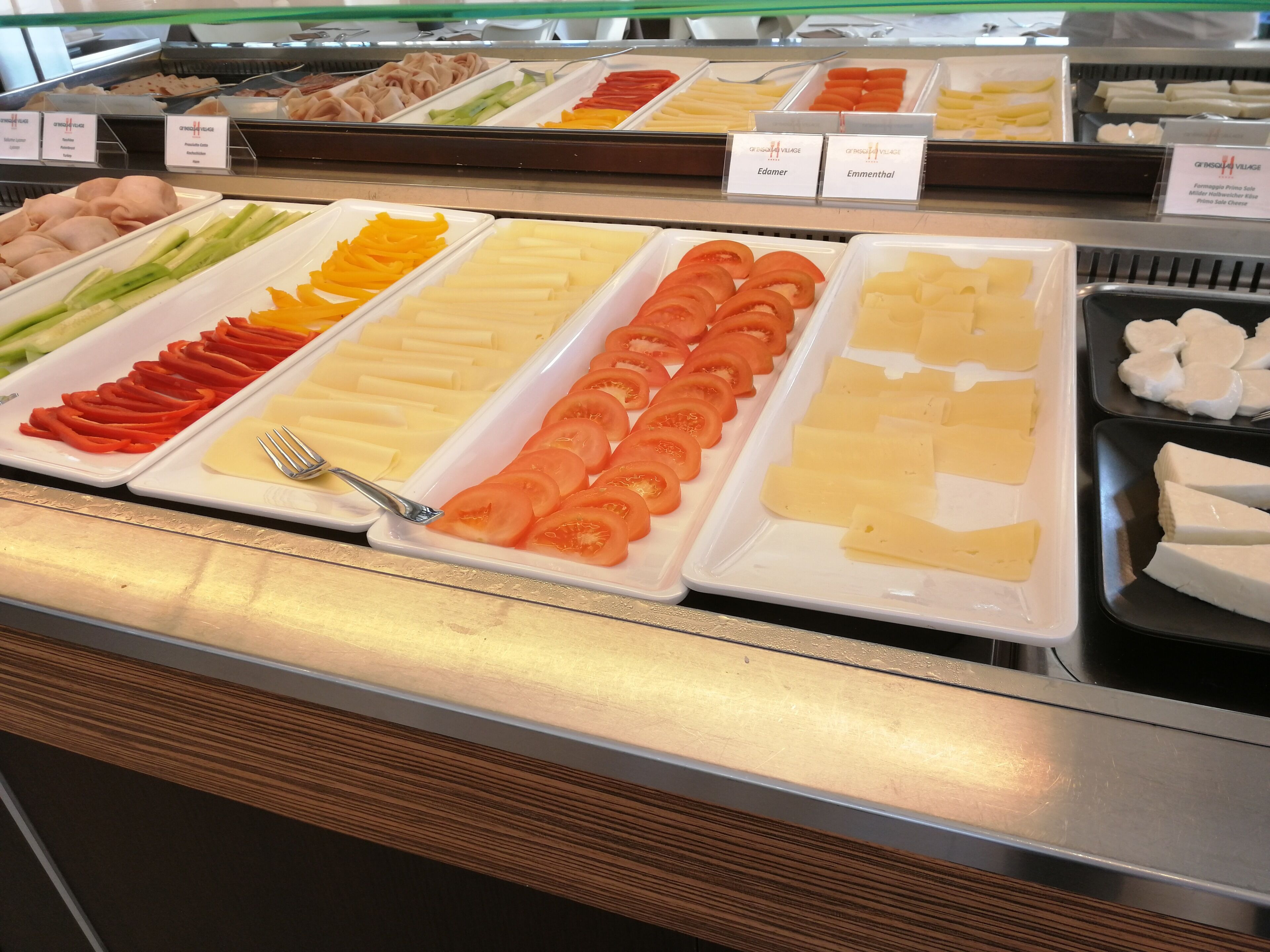 Un buffet proposant une variété d’aliments, notamment des tomates en tranches, du fromage et d’autres plats préparés.