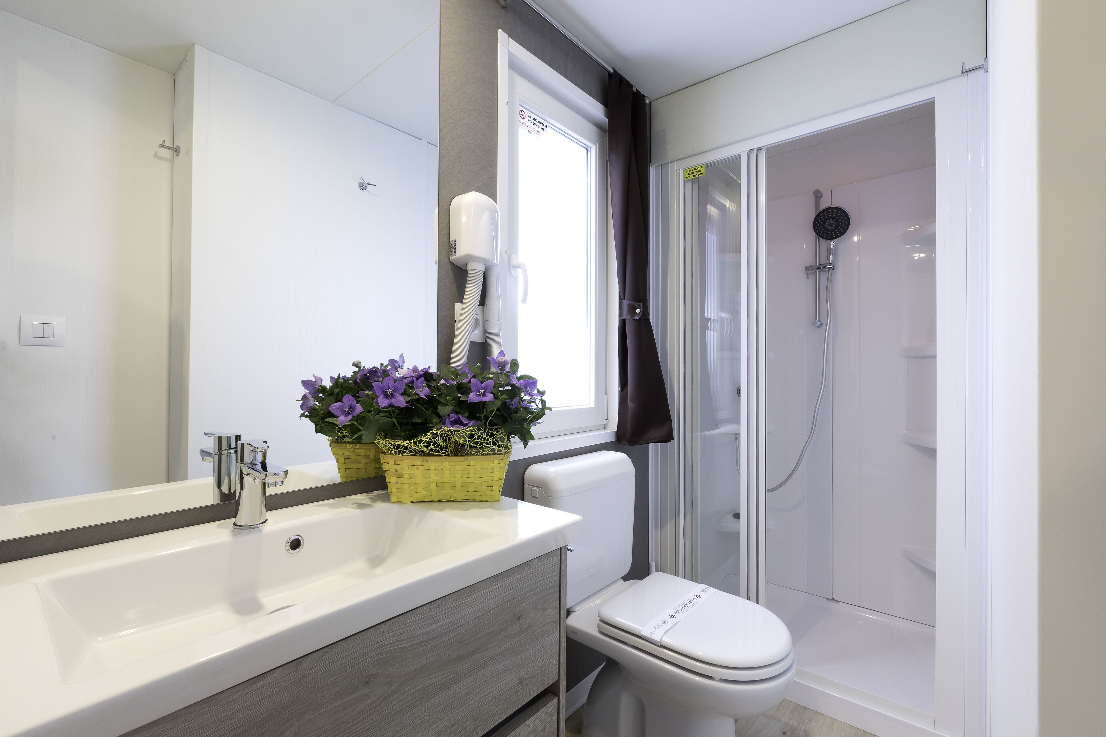 Ein modernes Badezimmer mit einem weißen Waschbecken, einer Toilette und einer Duschkabine.