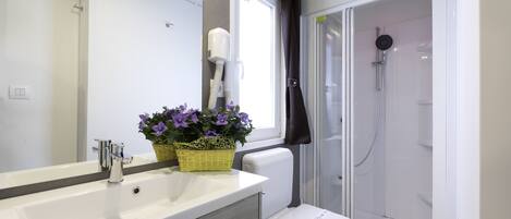 A modern bathroom with a white sink, a toilet, and a glass-enclosed shower.