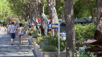 A tree-lined street with pedestrians and directional signs.