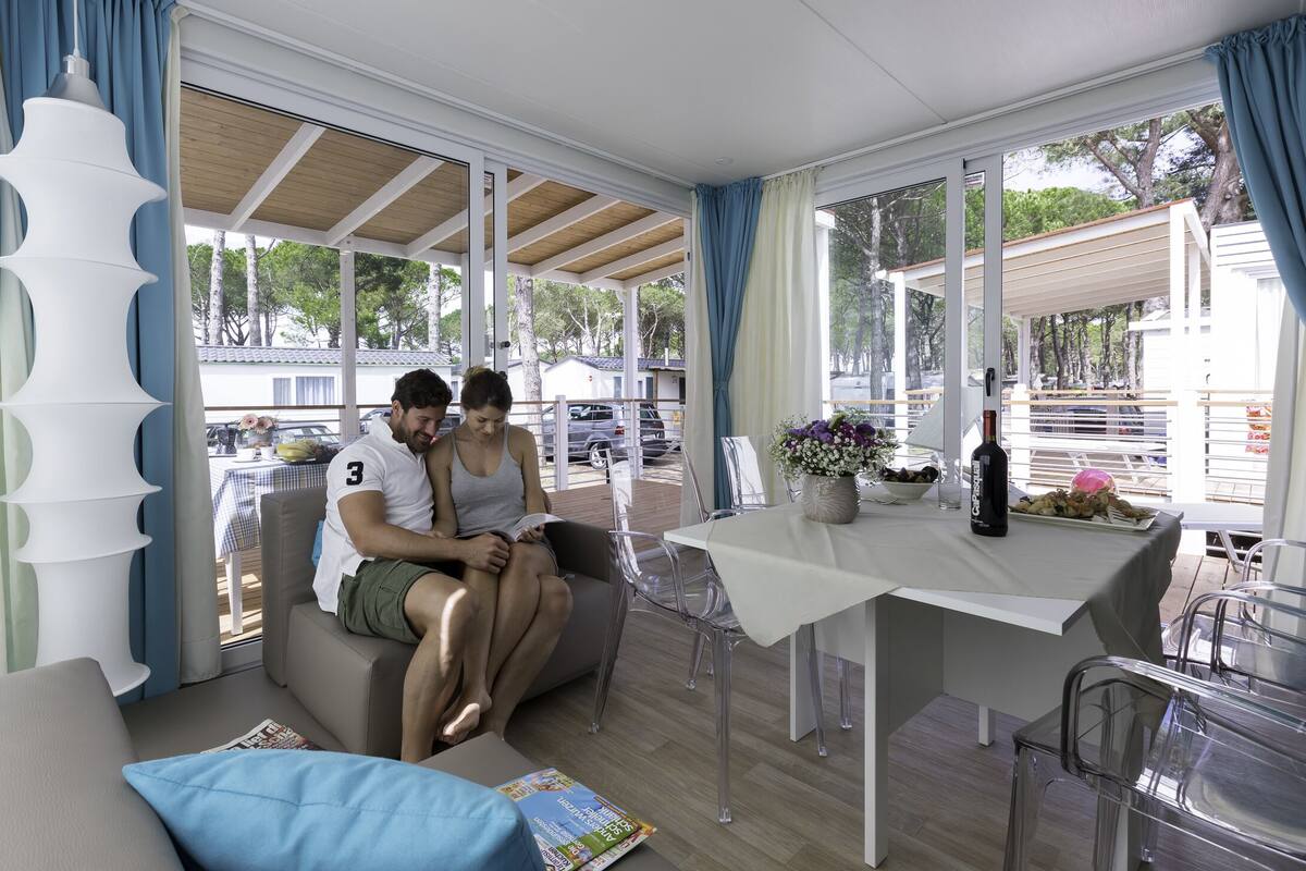 Een moderne, open woonkamer met een bank, eettafel en transparante stoelen.