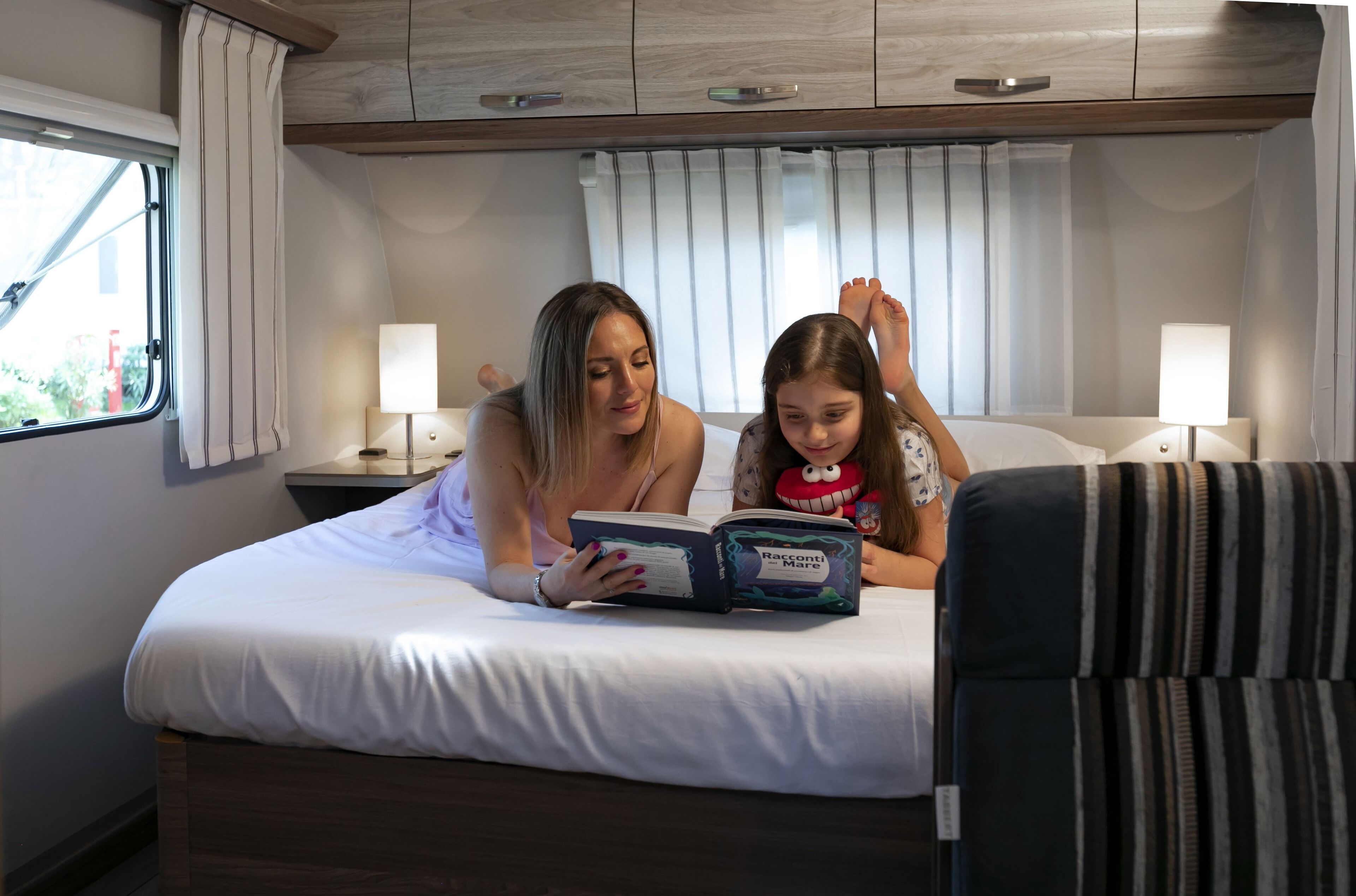 Een slaapkamer met een bed, twee bedlampen en een raam met gordijnen.