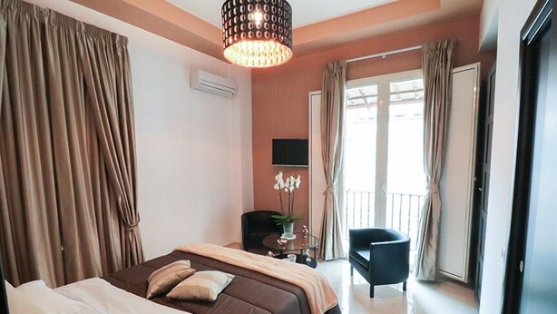 A hotel room with a large bed, a desk, a chair, and a balcony with curtains. - Terrazza Partenopea (Naples)