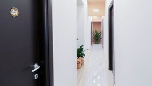 A modern hallway with a black door, white walls, and a marble floor. - Terrazza Partenopea (Naples)