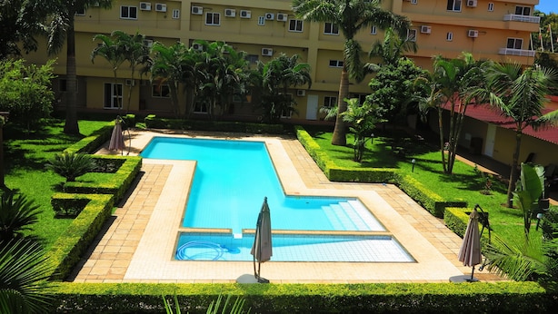 A hotel with a rectangular pool surrounded by manicured lawns and palm trees. - Hotel Castelo Branco (Chimoio)