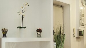 Un couloir avec un mur blanc, une horloge et une porte.