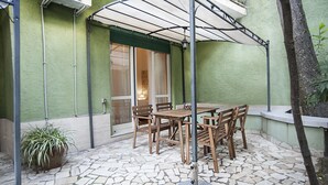 Une terrasse avec un sol en pierre, des meubles en bois et une plante en pot.