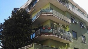 Un immeuble à plusieurs étages doté de balcons, d’une entrée sécurisée et d’un panneau indiquant « Stationnement interdit ».