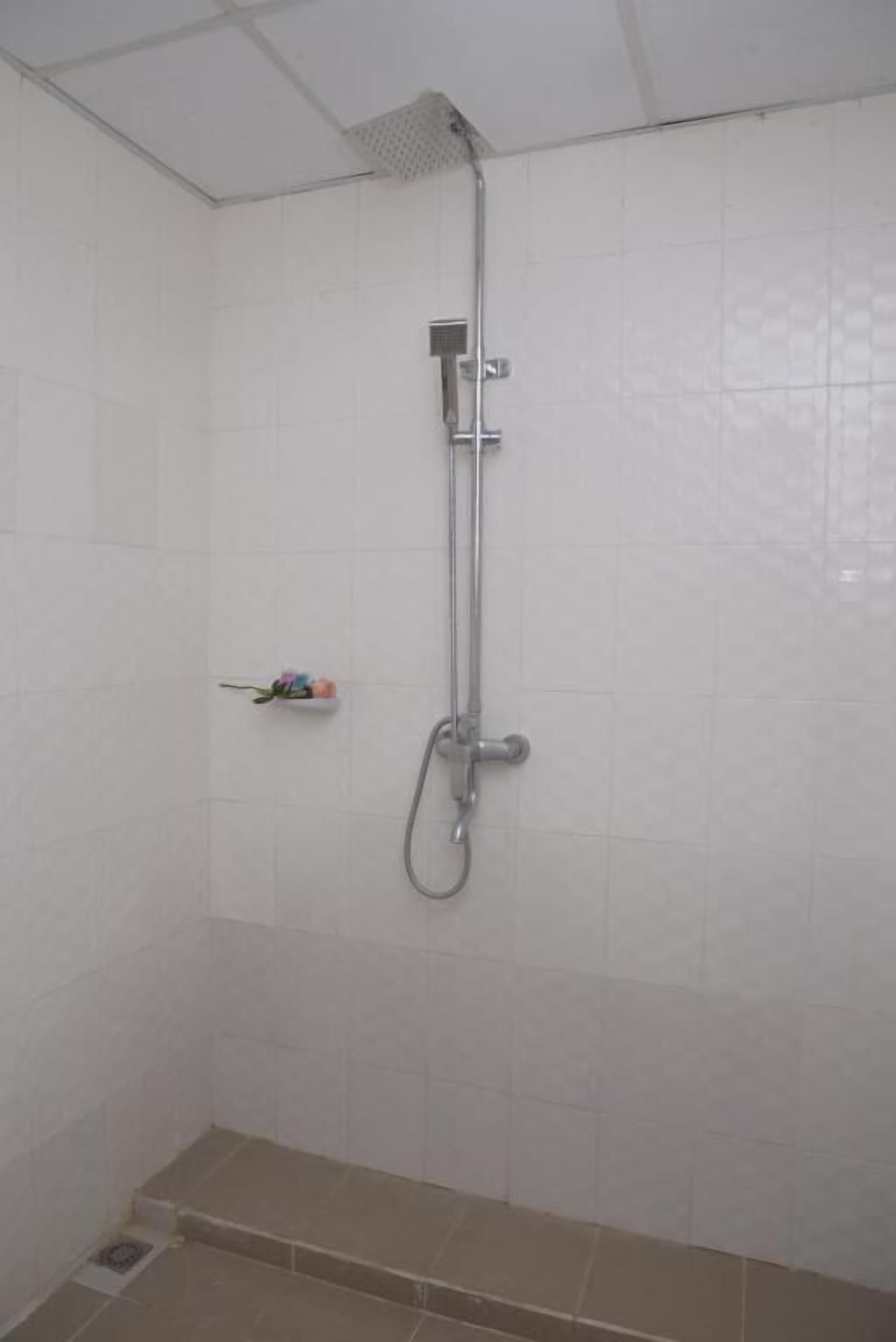 A shower area with a handheld showerhead and a wall-mounted faucet.
