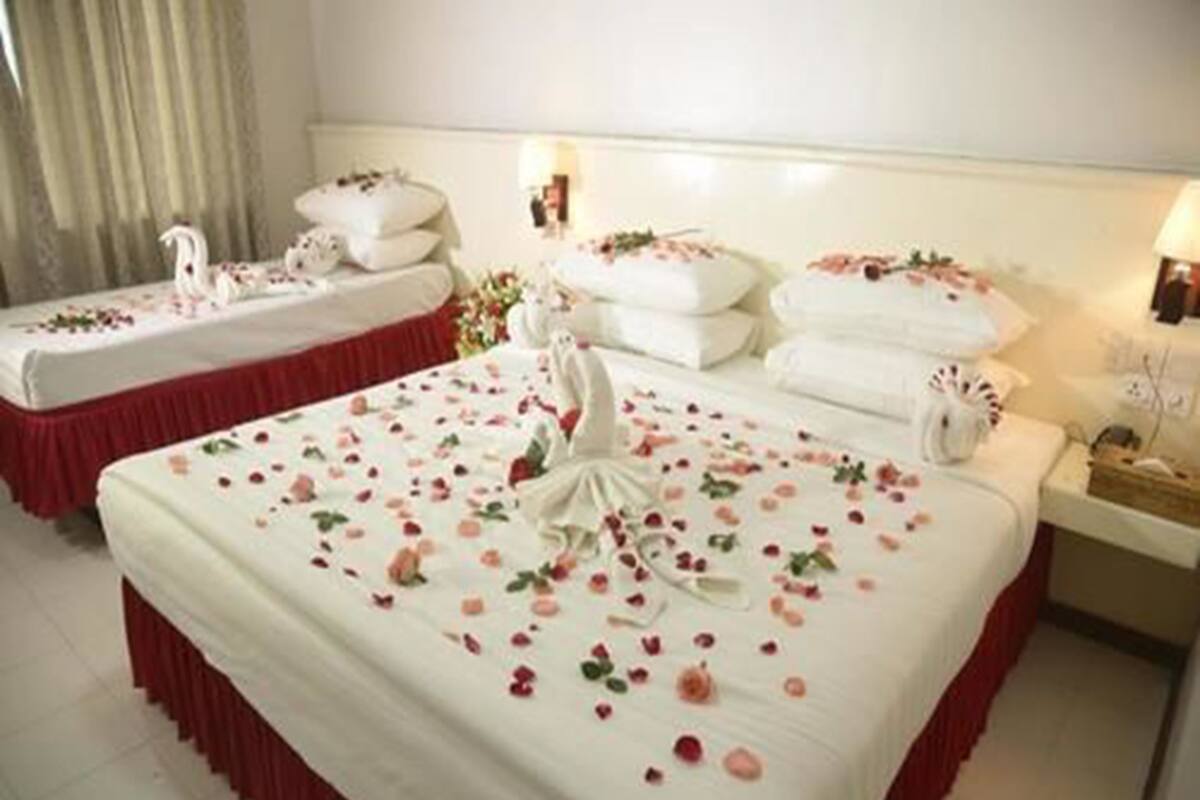A hotel room with two beds, each adorned with white linens and floral decorations.
