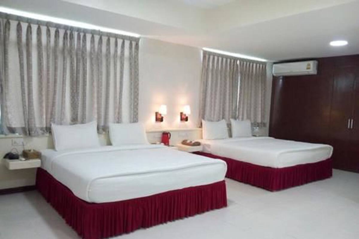 A hotel room with two beds, a wardrobe, and a nightstand with a lamp.