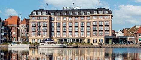 A hotel with a large building, a waterfront view, and a reflection in the water.