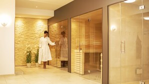 Un moderno vestíbulo de hotel con una pared de piedra, una zona de recepción y una puerta de cristal que da a una zona de duchas.