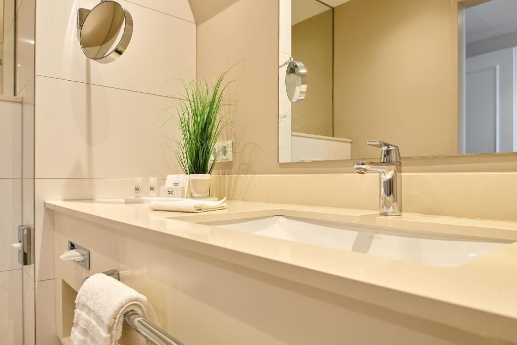 A modern bathroom with a double sink, a large mirror, and a towel rack.