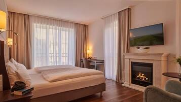 Quarto de hotel com cama, televisão sobre a lareira e uma escrivaninha com cadeira.