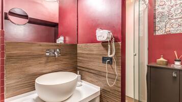 A modern bathroom with a large white sink, a handheld hair dryer, and a glass shower enclosure.