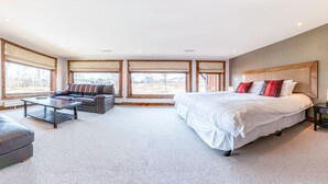 A modern hotel room with a large bed, a sofa, a coffee table, and a TV. - Yukimi 1 (Kutchan)