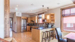 A modern kitchen with wooden cabinets, stainless steel appliances, and a central island with stools. - Yukimi 1 (Kutchan)