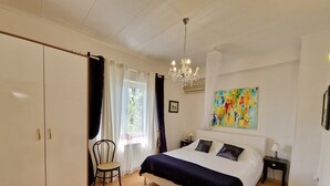 Un dormitorio con una cama grande, una silla, un escritorio y un cuadro en la pared.