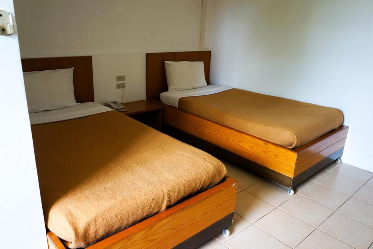Dos camas individuales con cabeceros de madera y ropa de cama color beige en una habitación de hotel.