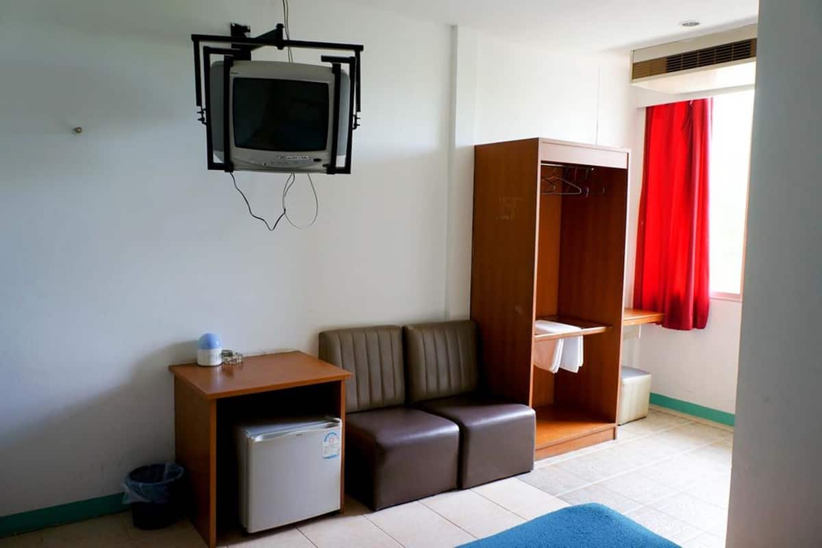 Una habitación pequeña con televisor, sofá, armario y un refrigerador pequeño.