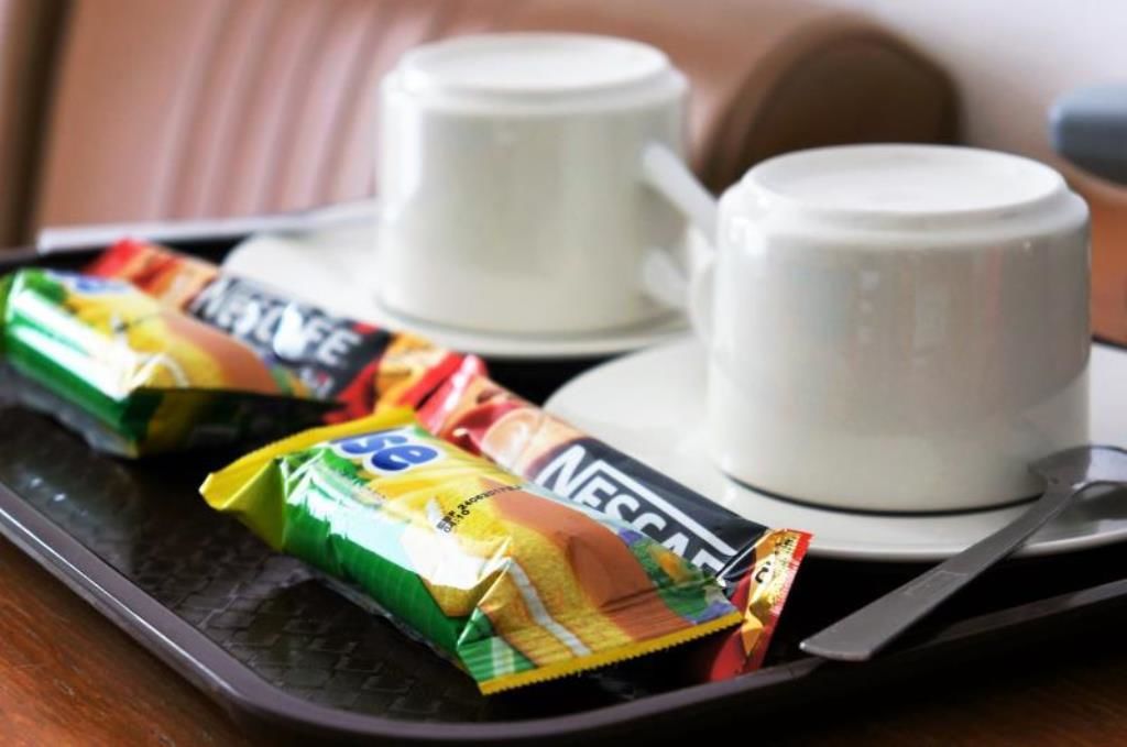 Een dienblad met twee witte kopjes en twee zakjes Nescafe oploskoffie.