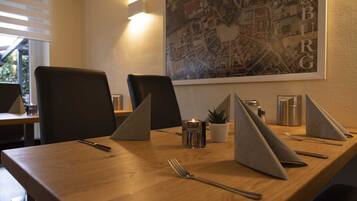 A conference room with a wooden table, black chairs, a laptop, a candle, a small plant, and a map of Dusseldorf on the wall.