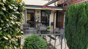 An outdoor patio area with a table and chairs, surrounded by greenery and a brick wall. - Hotel Rendsburg (Rendsburg)