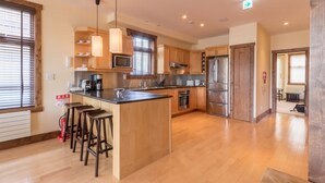 Una cocina moderna con armarios de madera, electrodomésticos de acero inoxidable y una isla central con taburetes de bar.