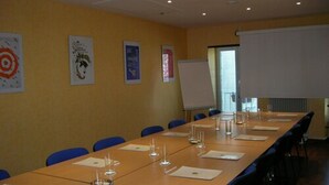 Een vergaderzaal met een lange tafel, blauwe stoelen en een whiteboard.