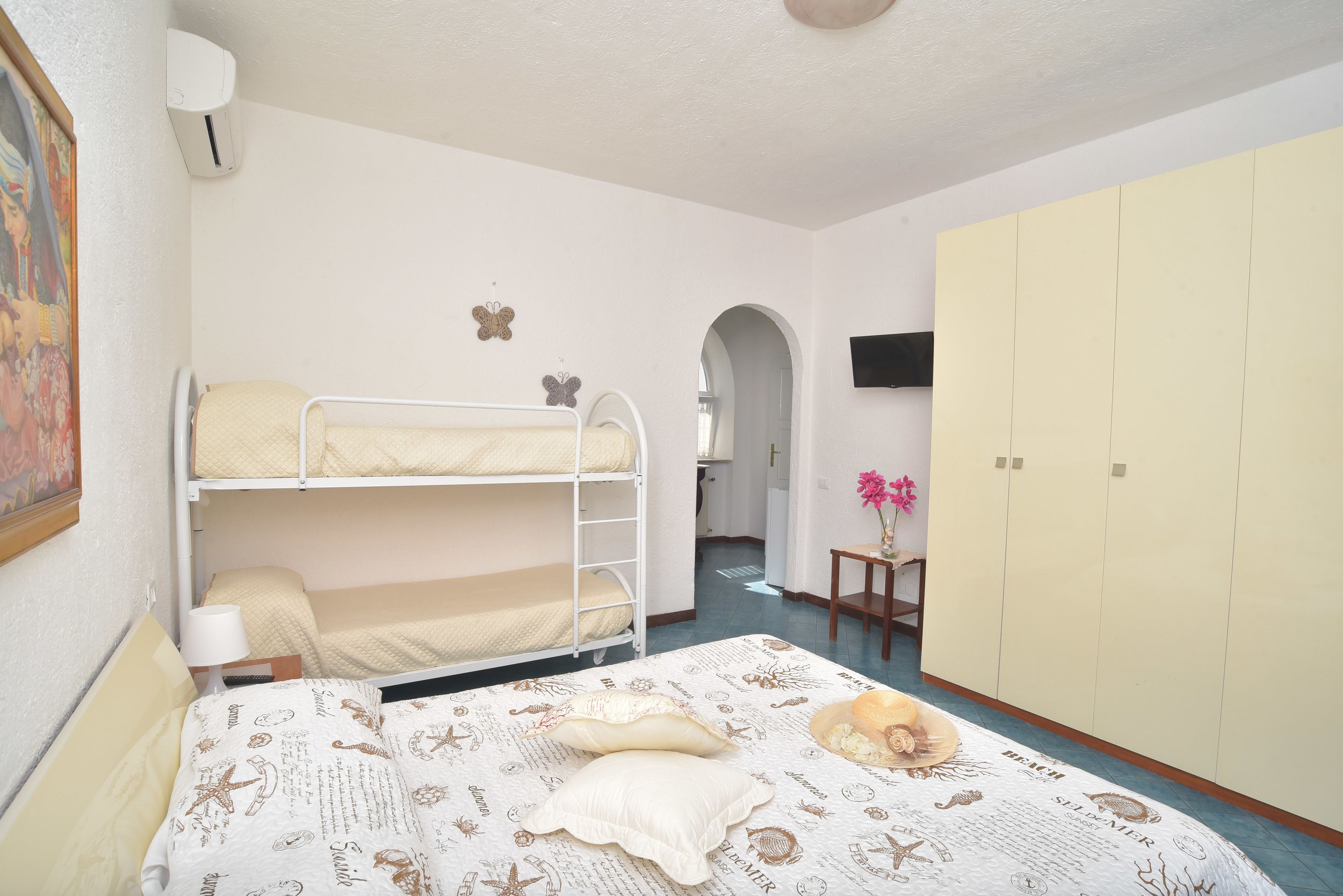 Une chambre avec des lits superposés, un bureau, une chaise, une télévision et une armoire.