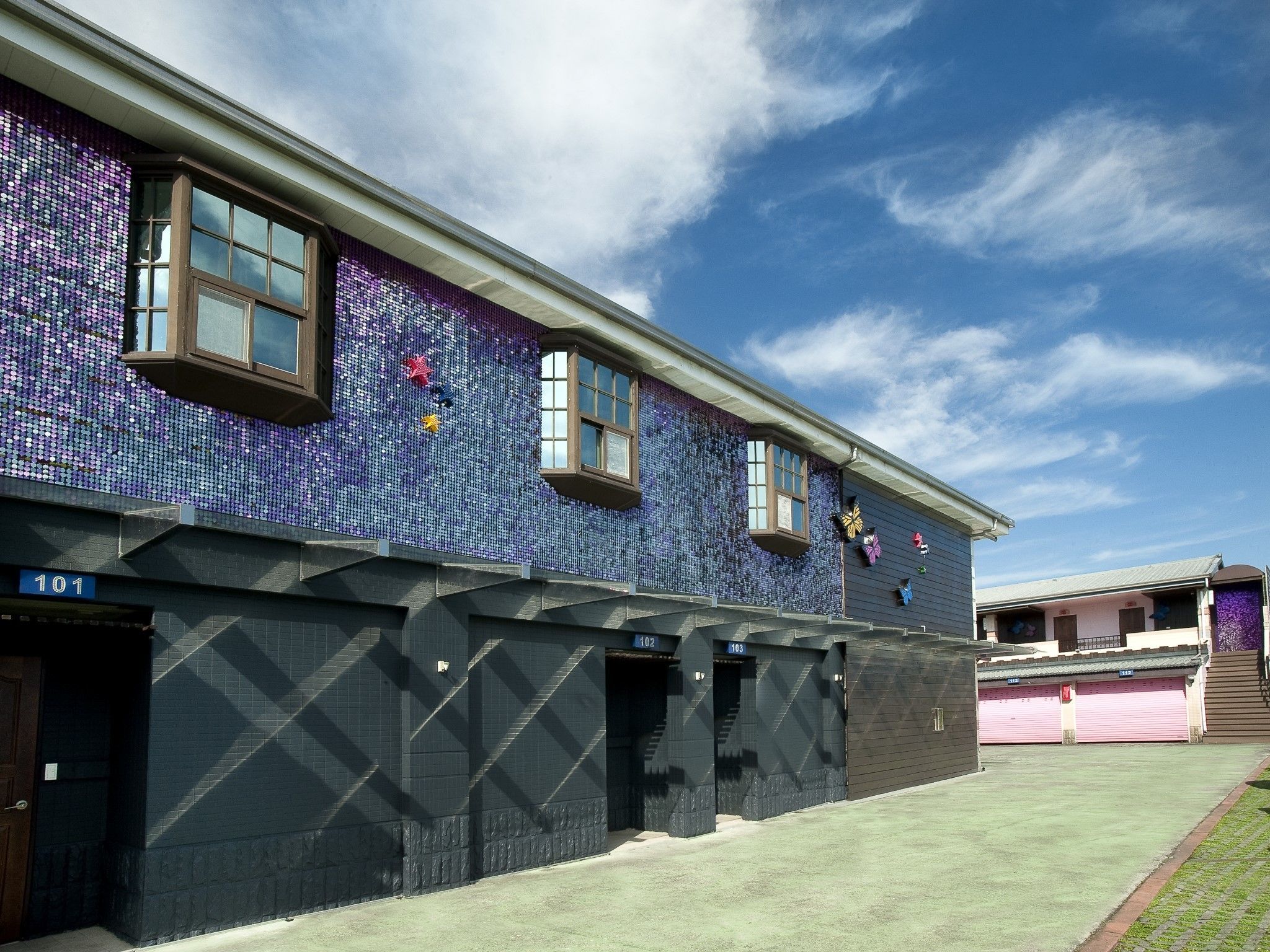 A building with a mosaic facade, numbered doors, and a clear sky.