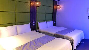 A hotel room with two beds, a green upholstered headboard, and two wall-mounted pendant lights.