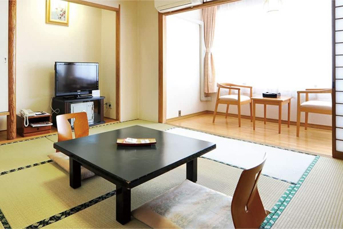 Una tradizionale stanza giapponese con pavimenti in tatami, un tavolino basso e porte scorrevoli.