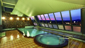 Una piscina al terrat amb vista a la ciutat al capvespre.