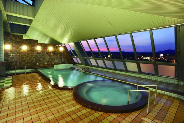 Una piscina en la azotea con vistas a la ciudad al anochecer.