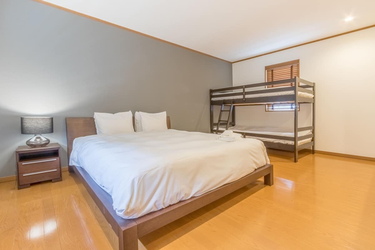 A bedroom with a wooden bed, a nightstand, and a bunk bed.