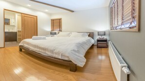 Une chambre avec un grand lit, un plancher en bois, une armoire intégrée, une table de chevet avec une lampe et un radiateur.
