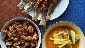 Ein Tisch mit einem Teller frittiertem Fisch, belegt mit knuspriger Gewürzmischung, einer Schale mit Oktopus und einer Schüssel Gemüsesuppe.