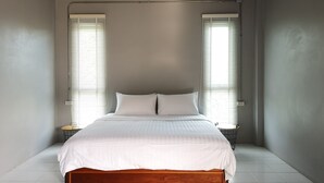 Une chambre à coucher avec un lit en bois, une literie blanche, deux tables de chevet et une lampe suspendue.