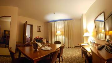 Une chambre d’hôtel équipée d’une table à manger, de chaises, d’un miroir, d’une lampe et d’un lit.