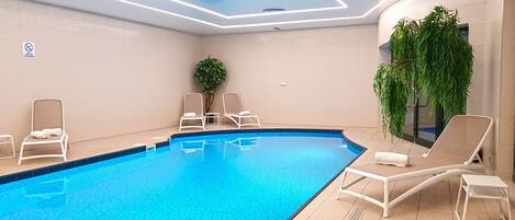 A swimming pool with lounge chairs and a potted plant.