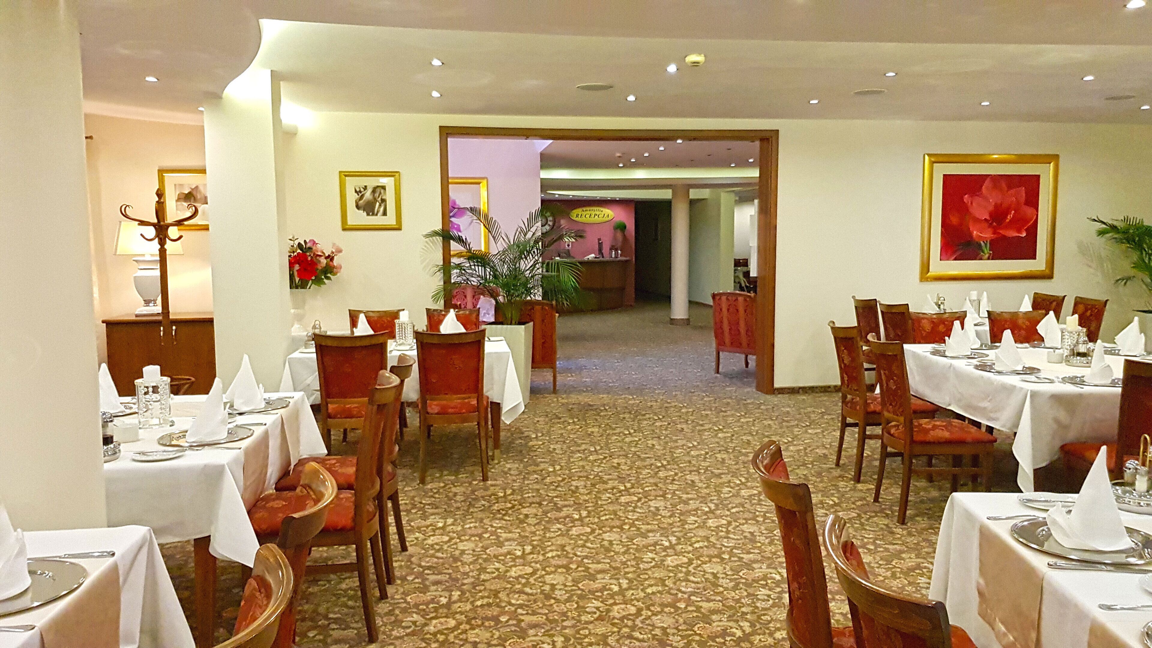 Comedor de hotel con varias mesas dispuestas para los huéspedes, sillas y suelo alfombrado.