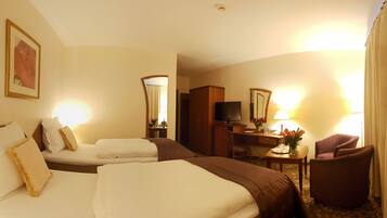 A hotel room with two beds, a desk with a chair, a television, and a mirror.