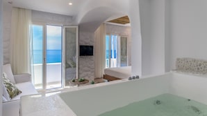 A modern bedroom with a large bed, a TV, and a view of the sea through a sliding door. - Cyano Suites (Naxos)