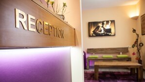 A reception area with a wooden reception desk labeled "RECEPTION" and a framed picture on the wall. - Hotel Am Ostpark (Munich)
