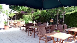 An outdoor patio with wicker furniture and a green canopy. - Hotel Am Ostpark (Munich)
