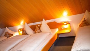 A cozy room with wooden paneling, a bed with white linens, and a bedside table with a lamp. - Hotel Am Ostpark (Munich)