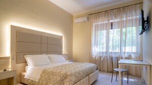 A bedroom with a bed, bedside table, chair, desk, and a TV mounted on the wall. - Villa Domus Salento Suites & Rooms (Lecce)